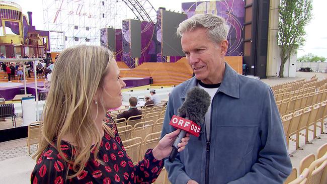 © ORF/Landesstudio Burgenland Eine ORF-Reporterin interviewt Alfons Haider vor der Bühne von „Ein Käfig voller Narren mit leeren Sitzreihen, Seebühne Mörbisch