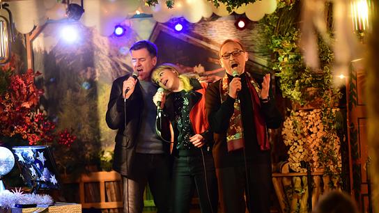 Die Kommissare Harald Neuhauser (Marcus Mittermeier, l.), Angelika Flierl (Bernadette Heerwagen, M.) und Ludwig Schaller (Alexander Held, r.) singen Karaoke in einer Münchner Kneipe.