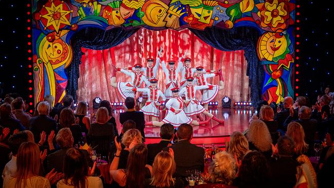 Die Faschingsgilde Völkermarkt in rot-weißen Kostümen formiert sich auf der "Narrisch Guat"-Bühne, während das Publikum applaudiert.