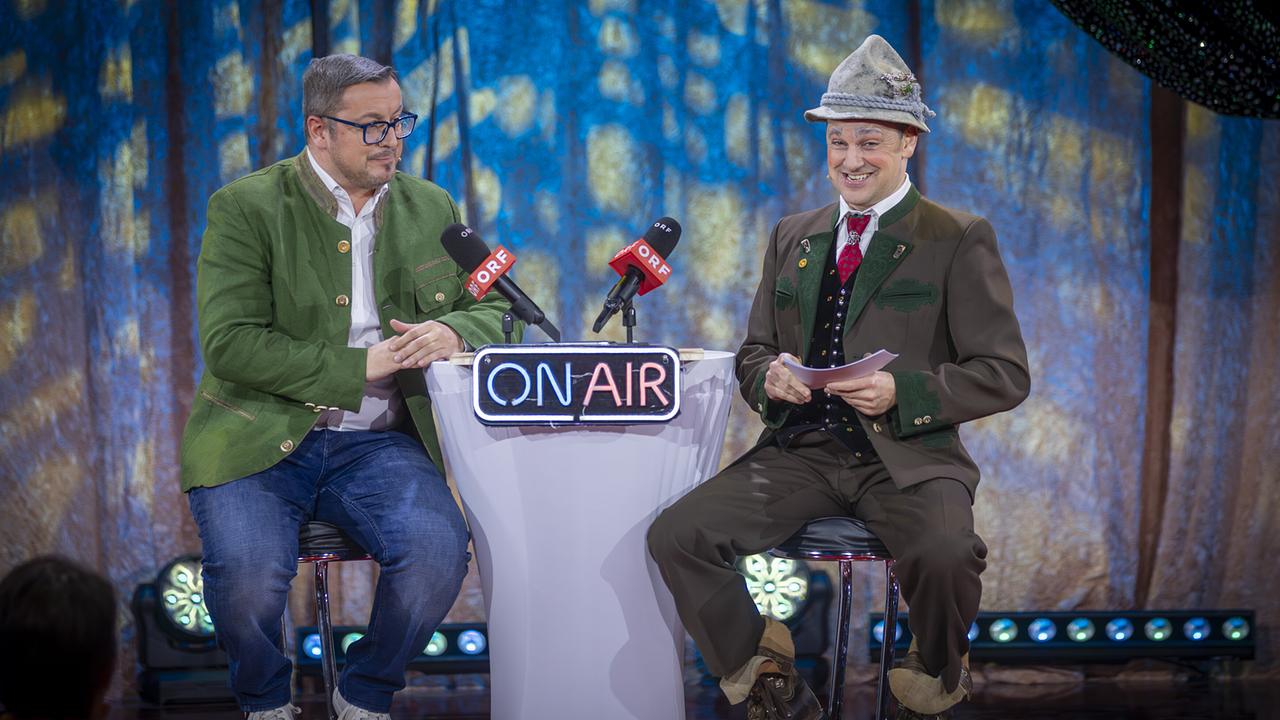 Peter Michael Kowal und Gunnar Zechner sitzen auf Barhockern an einem kleinen „ON AIR“-Tisch mit ORF-Mikrofonen und sprechen auf der "Narrisch guat"-Bühne.