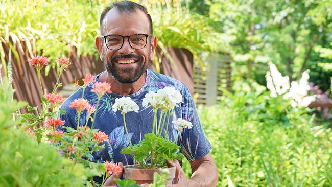 © Leopold Mayrhofer/Natur im Garten Karl Ploberger hält im Garten einen Blumentopf mit weißen und rosa Pelargonien.