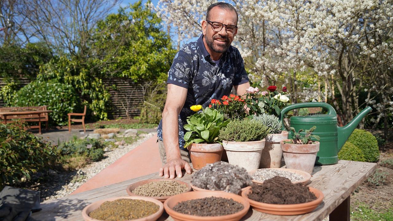 Karl Ploberger mit verschiedene Schalen Erde, Dünger und Töpfen blühender Rosen 