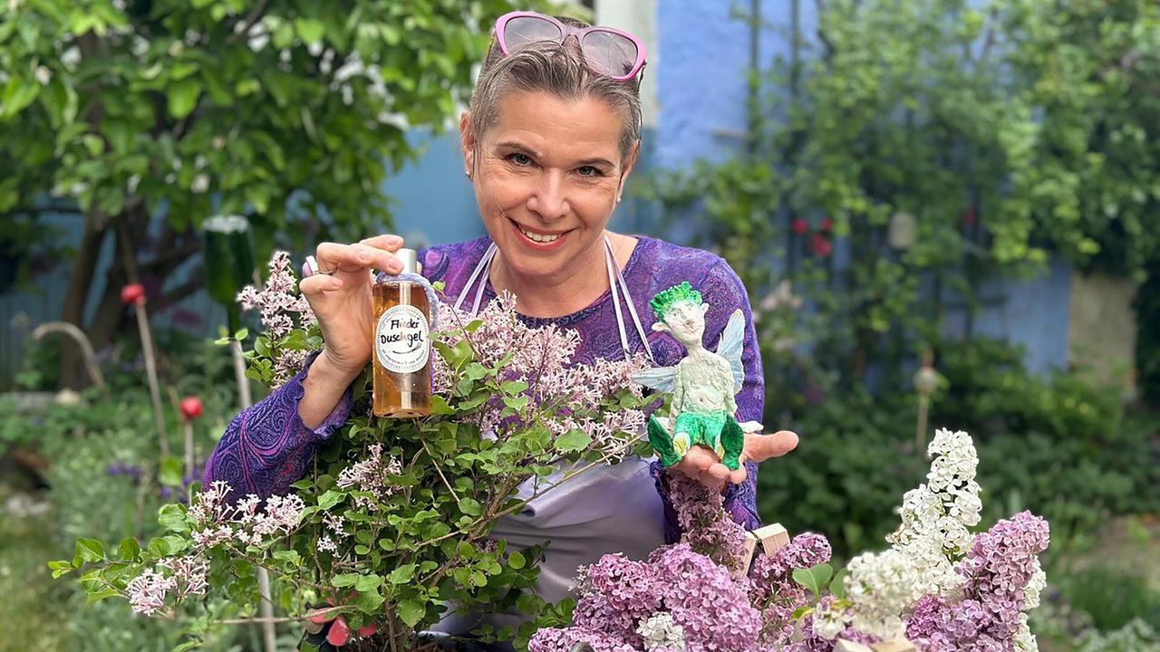 Uschi Zezelitsch hält eine Flasche mit Fliederöl in der Hand