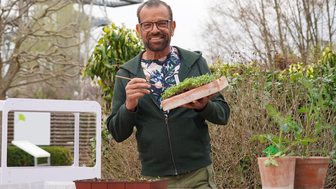 © Leopold Mayrhofer/Natur im Garten Karl Ploberger im Freien vor Sträuchern zeigt das Pikieren von kleinen Pflanzen.