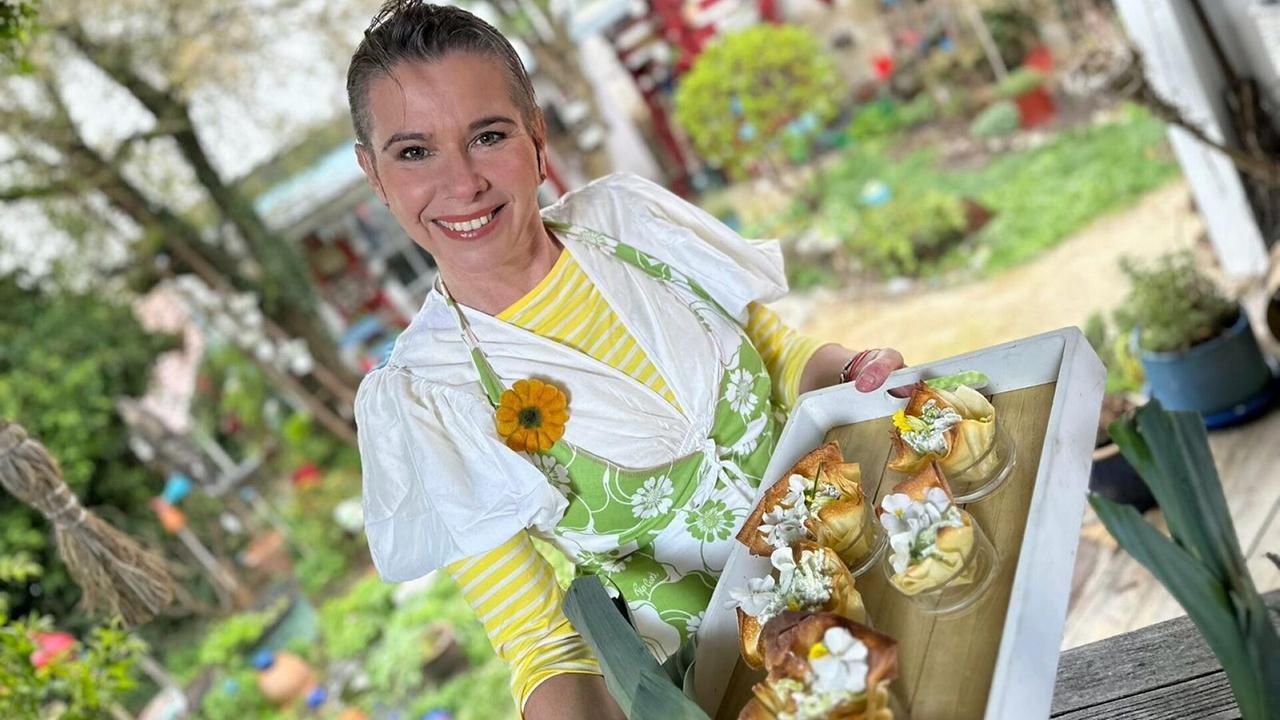 Kräuterhexe Uschi Zezelitsch hält ein Tablett mit mehreren dekorativ angerichteten Lauchrosen in der Hand