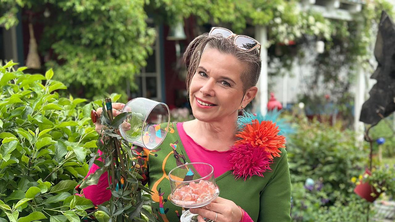 Uschi Zezelitsch hält eine Glasschale mit ihren Fruchtgummis im Garten stehend.