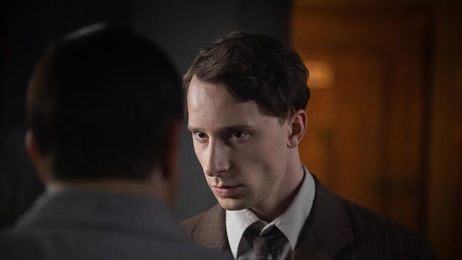 Junger Mann schaut mit ernstem Blick zu einem Mann, der von hinten zu sehen ist