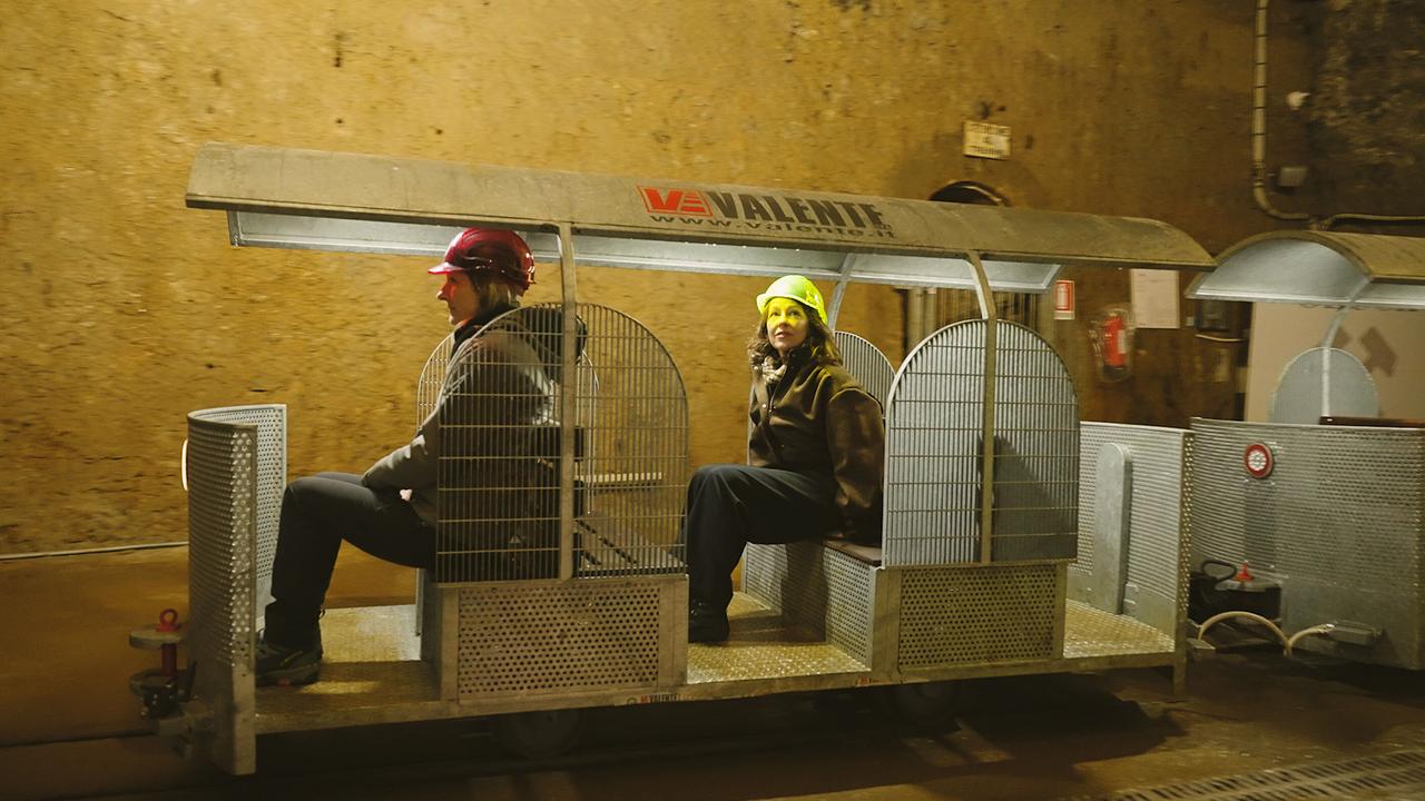 Julia Cencig unterwegs mit Bergwerksführerin Leila Meroi mit Schutzhelmen in einem kleinen Grubenwagen im Bergwerk Cave del Prebil 