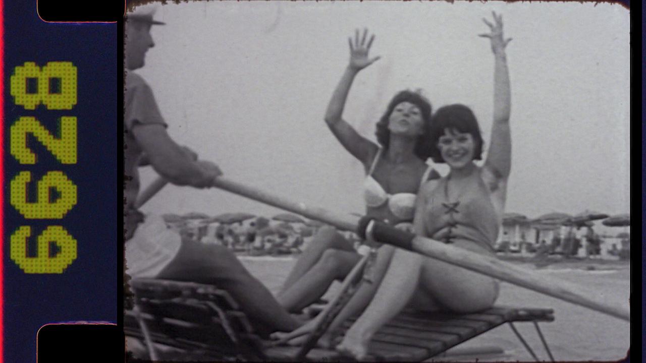 Archivbild: Adriaurlaub am Strand mit zwei winkenden Frauen auf einem Ruderboot