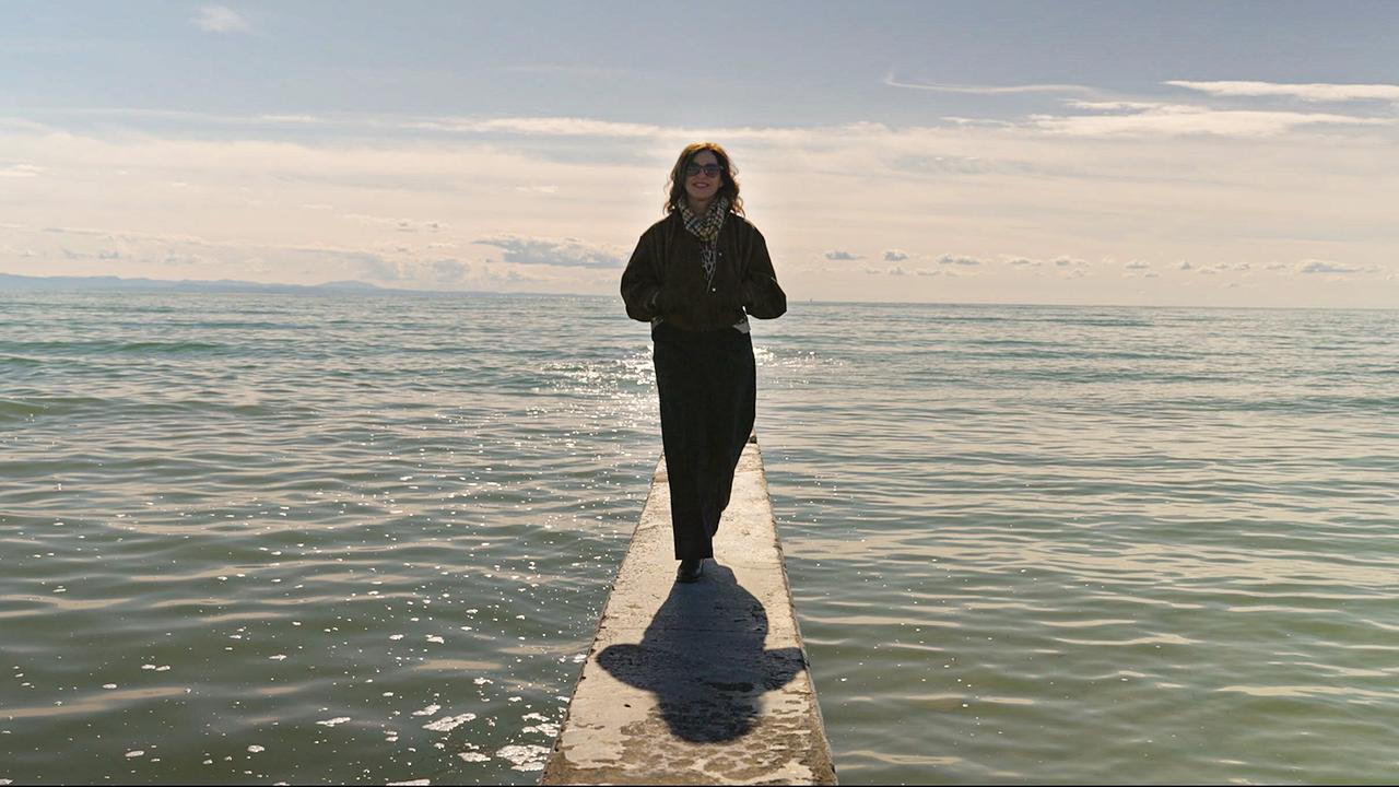 Julia Cencig steht auf einem Steg im Meer und blickt auf den Strand von Lignano.