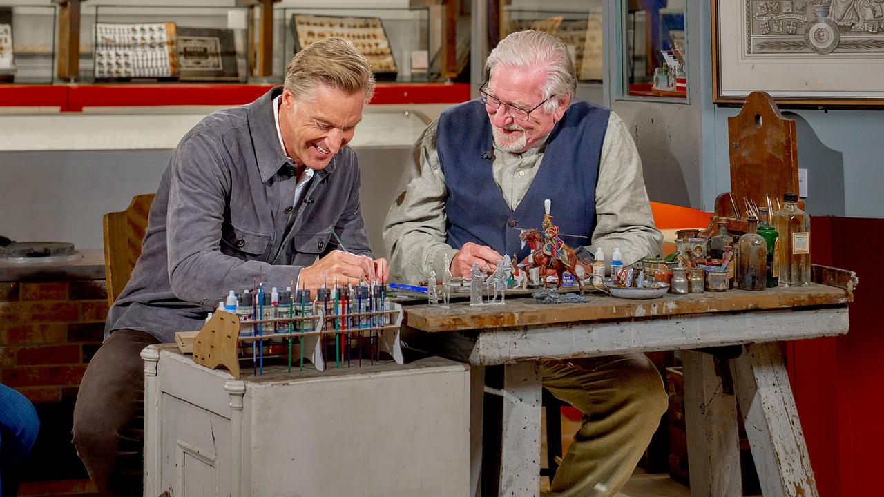 © ORF/Alois Kuschetz Hans Knauß und Franz Rieder sitzen an einem Arbeitstisch und bemalen kleine Figuren in einer historischen Werkstattumgebung.