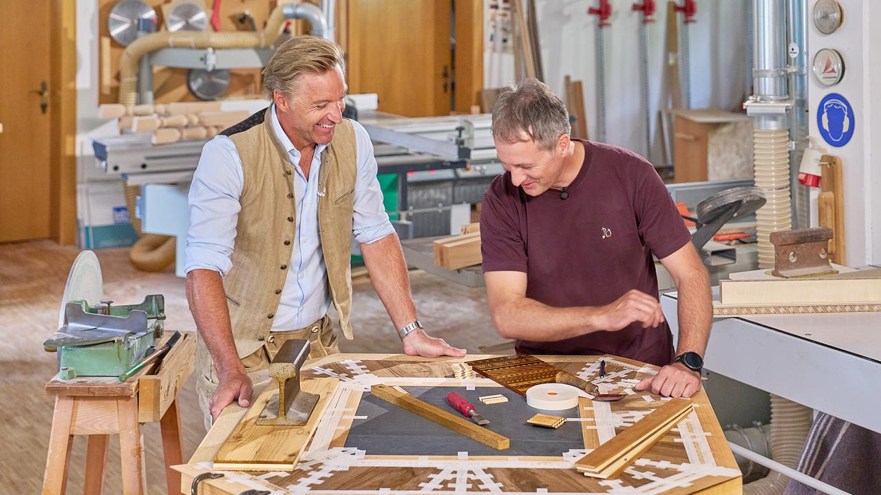 In einer Tischlerwerkstatt arbeiten Hans Knauß und Markus Juen gemeinsam an einem kunstvollen Holztisch.