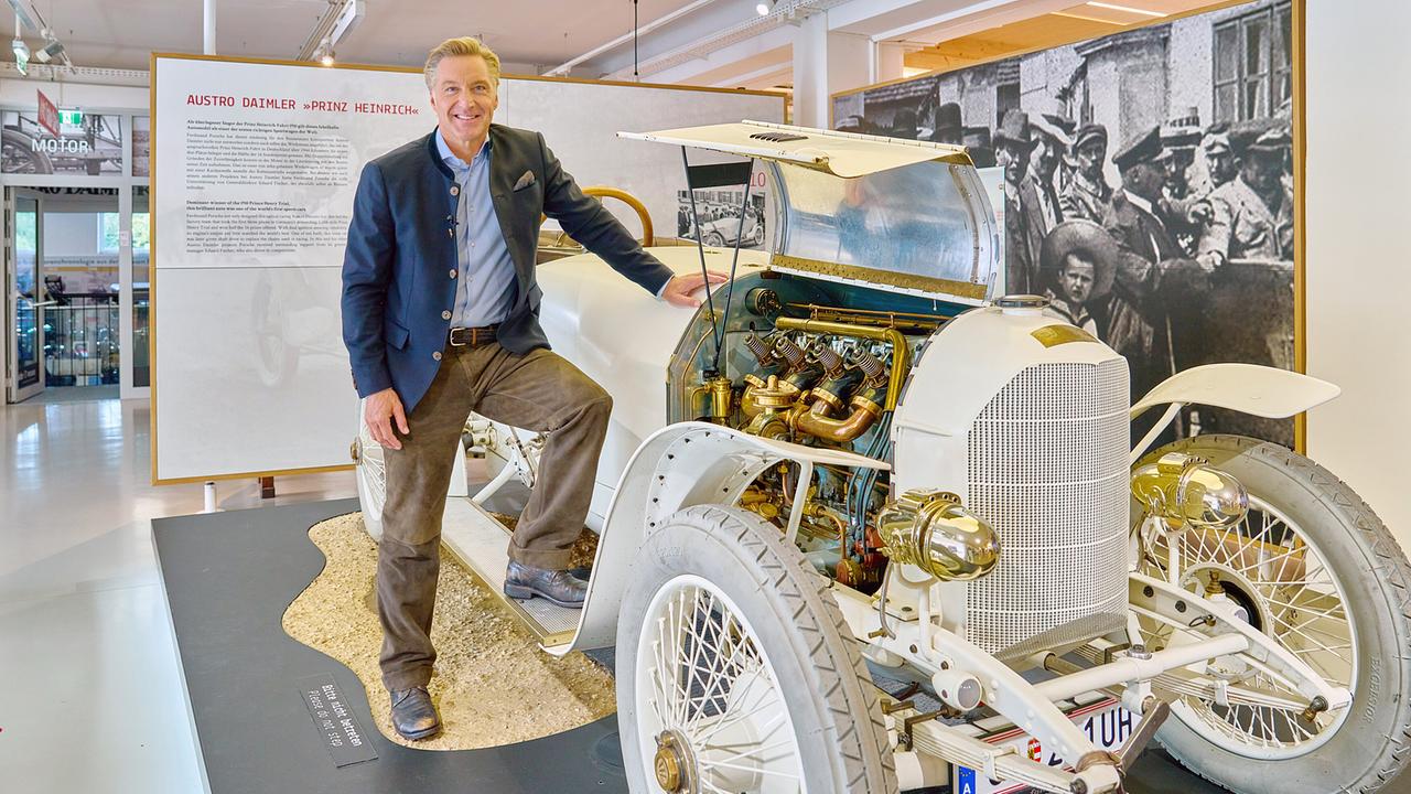 © ORF/Landesstudio Steiermark/Alois Kuschetz Hans Knauß steht neben einem historischen Austro-Daimler-Oldtimer mit offenem Motorraum.