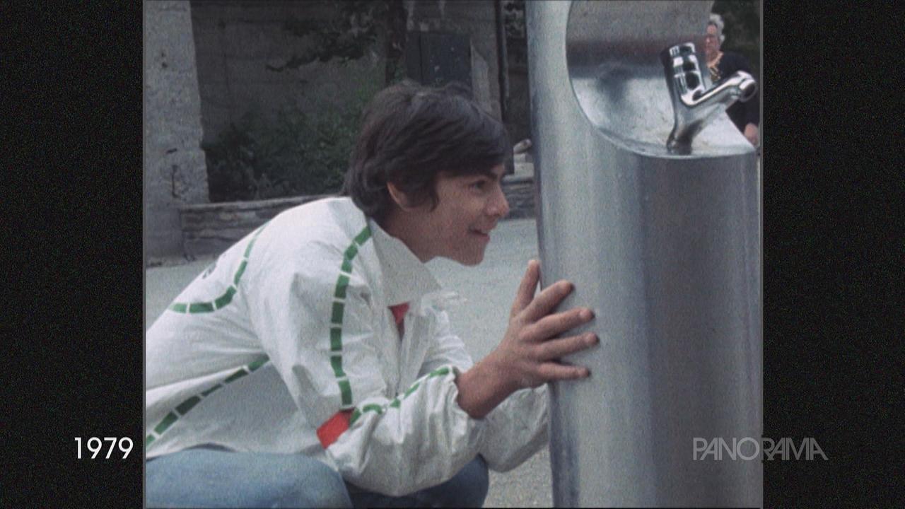 Ein junger Bursche versteckt sich hinter einem Wasserspender.