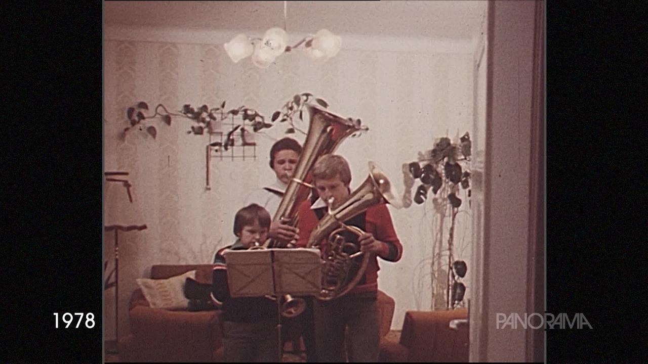 Am Bild aus dem Jahr 1978 sind drei Kinder mit Blasinstrumenten beim Üben im Wohnzimmer.