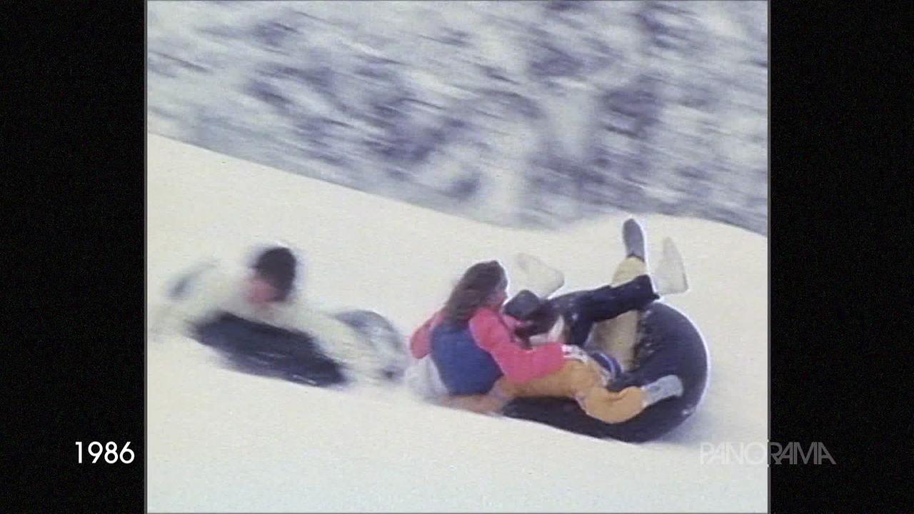 Am Bild aus dem Jahr 1986 rutschen Menschen auf großen, aufgeblasenen Reifen im Schnee bergab.