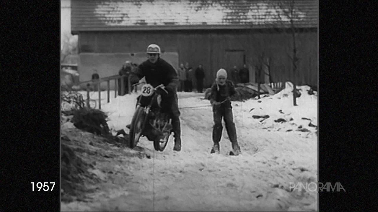 Am Bild aus dem Jahr 1957 ist ein sogenanntes Ski-Jöring-Gespann zu sehen. Ein Motorradfahrer zieht mit einem Seil einen Schifahrer über eine Schneestrecke.