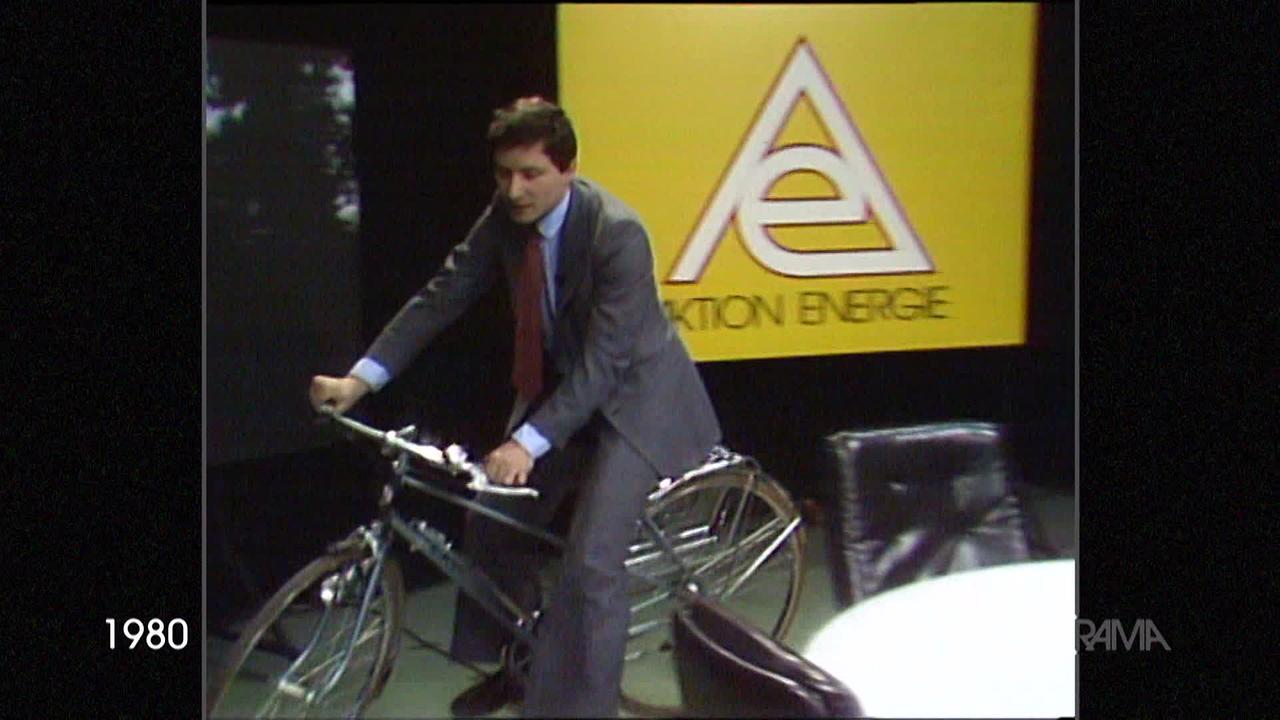 © ORF Am Bild aus dem Jahr 1980 ist Robert Hochner, ein bekannter "Zeit im Bild" Moderator, auf einem Fahrrad im Studio. Er fährt um einen runden Tisch. Im Hintergrund ist ein großes Schild mit der Aufschrift Aktion Energie.