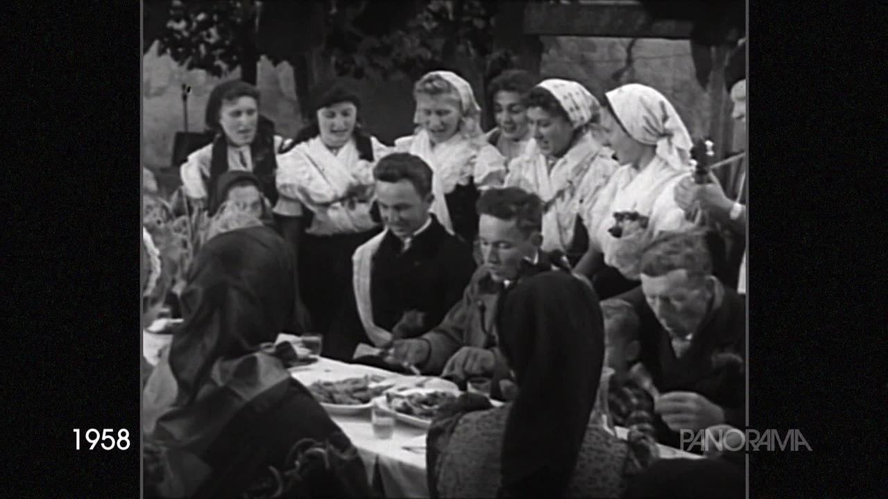 © ORF Auf dem schwarz-weiß-Bild aus dem Jahr 1958 ist eine folkloristische Gruppe zu sehen. Die Frauen tragen Kopftücher und burgenländischeTracht. Es wird gerade musiziert, gesungen und gegessen.