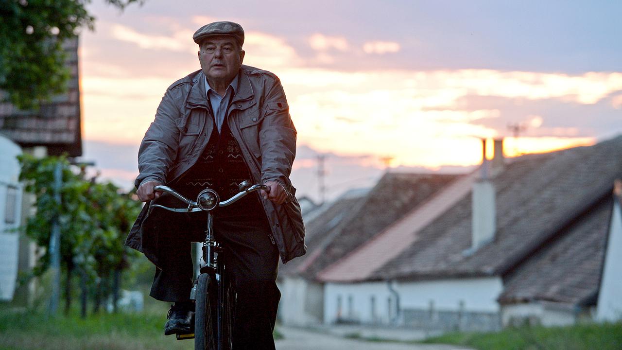 Simon Polt fährt bei Sonnenuntergang mit dem Fahrrad durch eine dörfliche Straße.