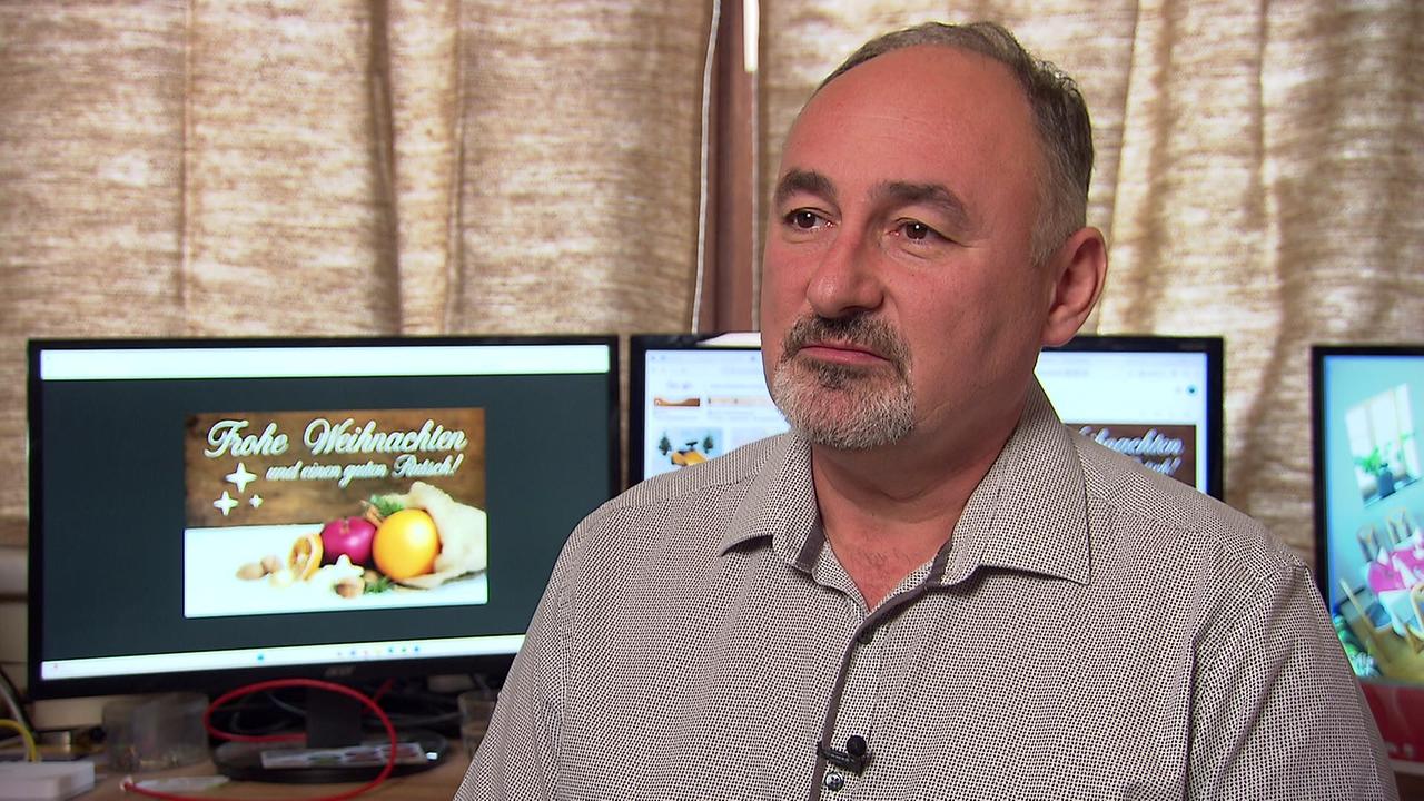 © ORF Gastronom Herr. B. sitzt beim Interview in einem Büro, im Hintergrund sind mehrere Monitore mit weihnachtlichen Motiven zu sehen.