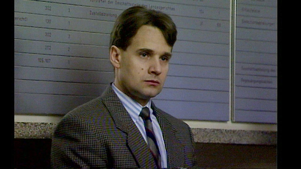 © ORF Nahaufnahme von Tibor Foco im Anzug vor einer Wand mit einer großen Tafel