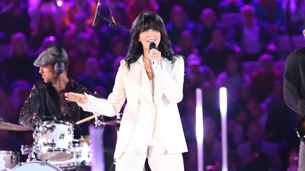 Nena im weißen Anzug steht auf der Bühne beim "Schlagerbooom Open Air 2026", singt ins Mikrofon und wird von einer Band vor einem violett beleuchteten Publikum begleitet.