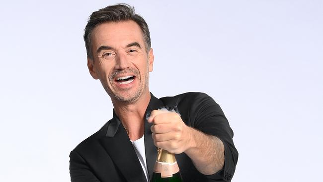 Florian Silbereisen öffnet schwungvoll eine Sektflasche vor hellem Hintergrund.