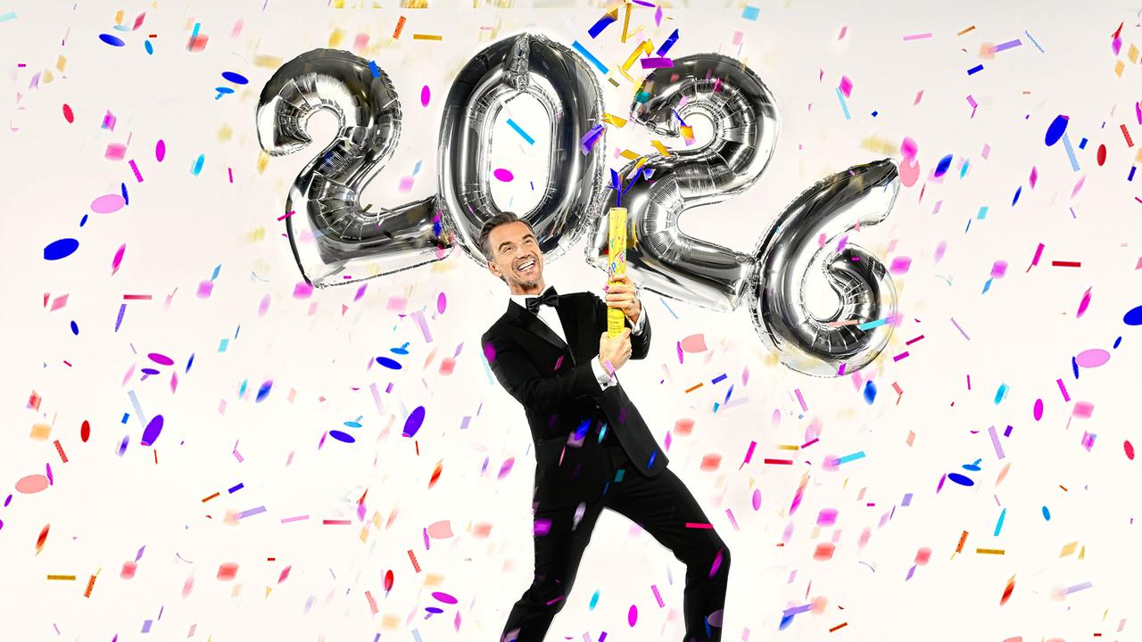 Florian Silbereisen steht vor großen „2026“-Ballons und sprüht Konfetti mit einer Dose in die Luft.