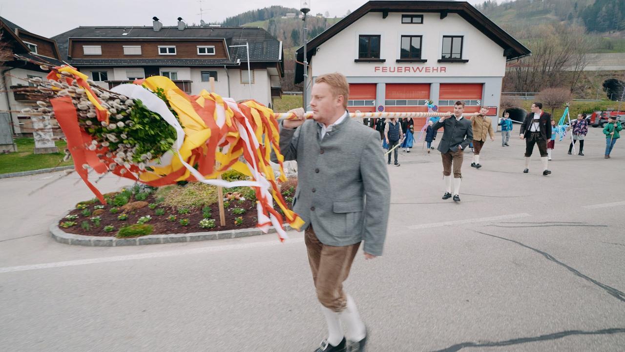 Ein junger Mann trägt die 16 Meter lange Palmstange mit einem Kollegen vom Feuerwehrhaus zur Kirche.