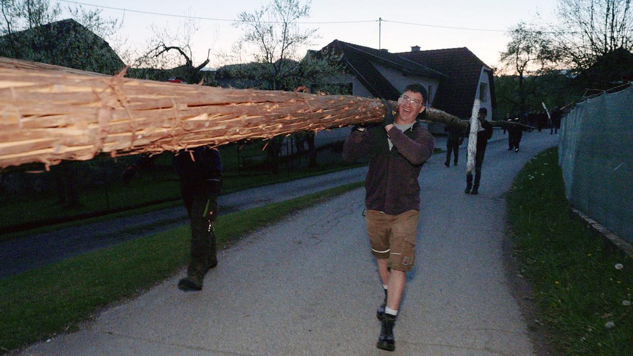 Eine Fackelträger lacht beim Tragen der schweren Fackel auf seiner Schulter.