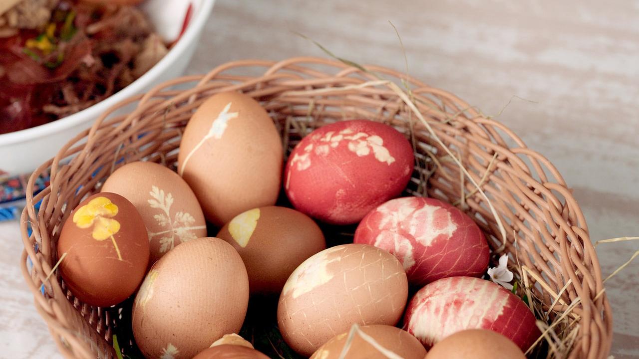 Ein Korb mit natürlich gefärbten Ostereiern mit floralen Mustern in verschiedenen Farben 