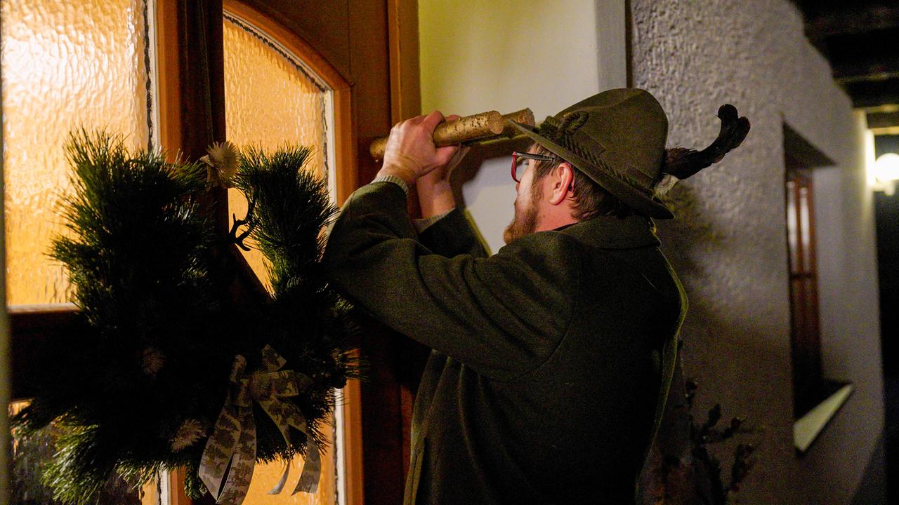 Ein Klöckler mit grünem Hut klöckelt an einer Tür