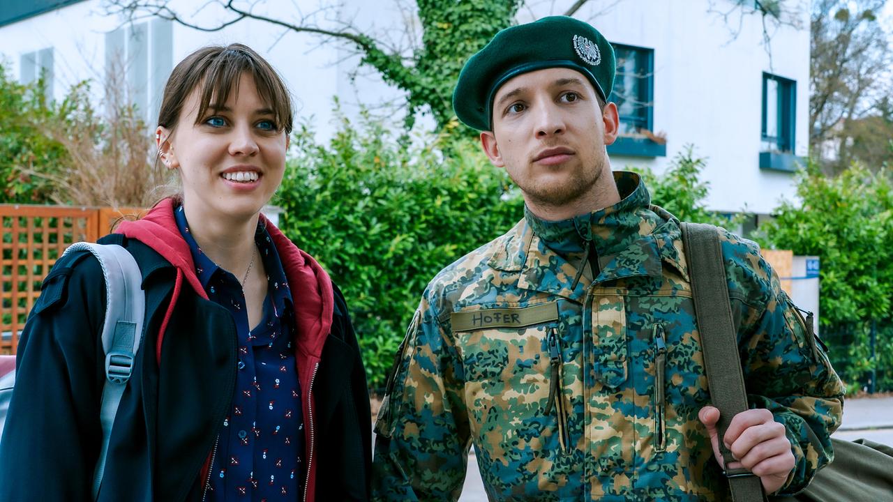 © ORF/BR/Cult Film/Petro Domenigg Die junge Hedwig Schaller steht draußen auf einer Wohnstraße neben dem Soldaten Andreas Hofer in Tarnuniform und Barett.