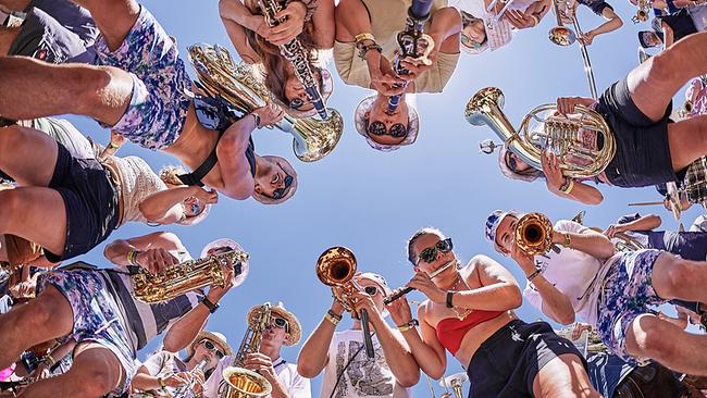 © ORF/Woodstock der Blasmusik/Klaus Mittermayr Eine Gruppe von Blasmusikerinnen und -musikern steht im Kreis unter blauem Himmel und spielt nach unten zur Kamera.