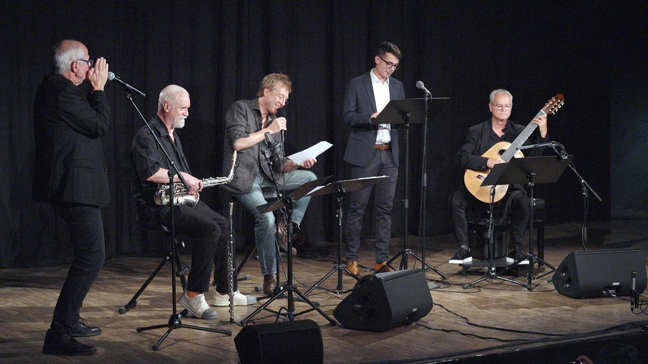 © ORF/Landesstudio Kärnten Die Sonusiade 2026 - Ich bin mehr Dichtung mit Max Müller und Musikern mit Saxofon und Gitarre und Sprechern auf der Bühne.