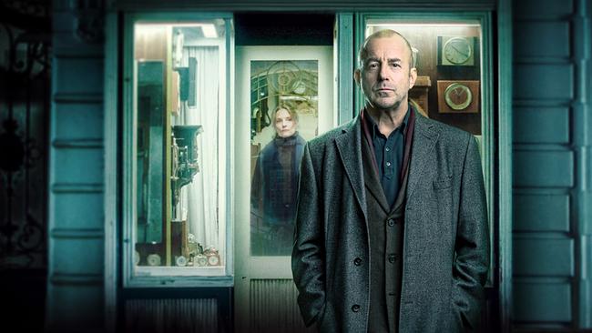 © ORF/Aichholzer Filmproduktion Richard Brock steht vor einem Schaufenster mit Uhren und mechanischen Objekten in einer nächtlichen Straße, im Geschäft steht Sara Roth.