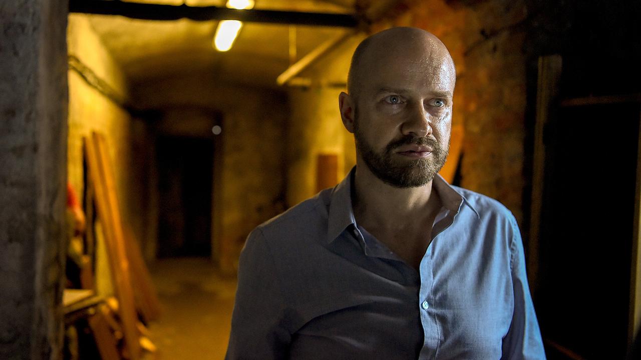 Marc Nymann steht in einem schmalen, schwach beleuchteten Kellergang.