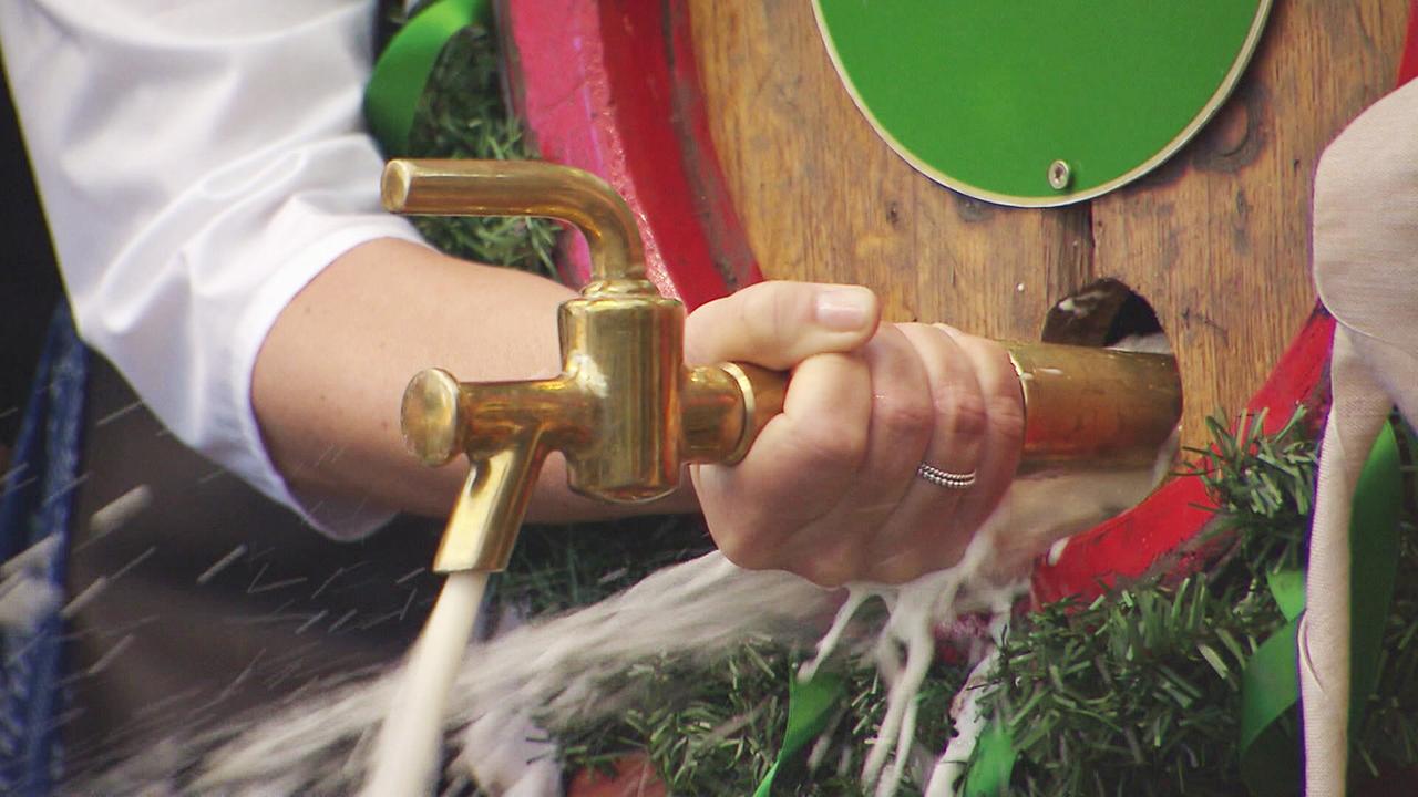 © ORF/Landesstudio Steiermark Eine Person zapft Bier aus einem kunstvoll dekorierten Holzfass.