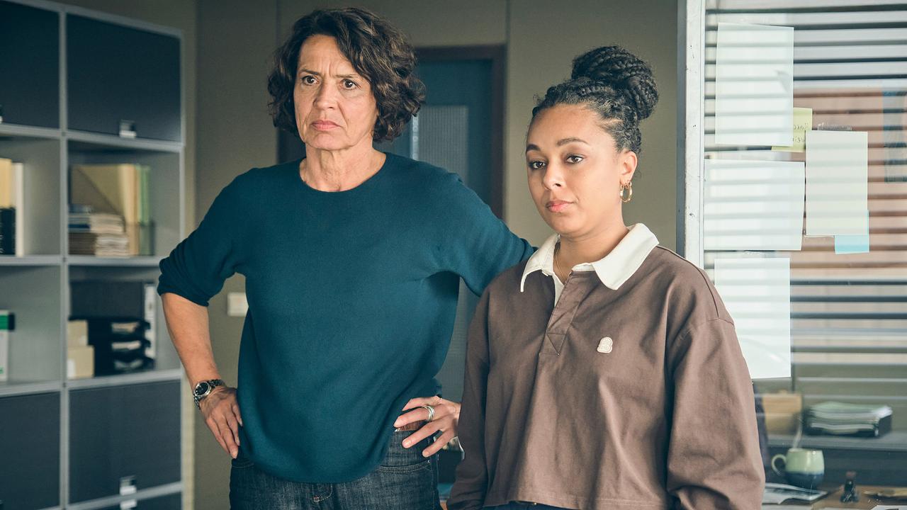 Lena Odenthal und Mara Hermann stehen nebeneinander in einem Büro, schauen nach vorne und fragen sich, ob sie ihrem jungen Kollegen ein Geheimnis anvertrauen können.