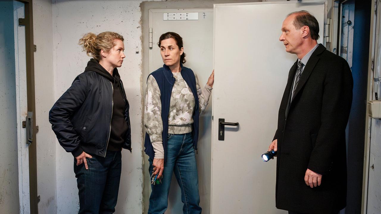 Leonie Winkler und Peter Schnabel bekommen von der Hausmeisterin den Keller eines Wohnhauses gezeigt.