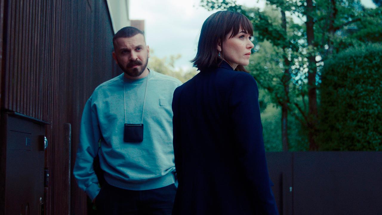 Hamza Kulina und Maryam Azadi stehen im Freien neben einem modernen Gebäude und einem Park.