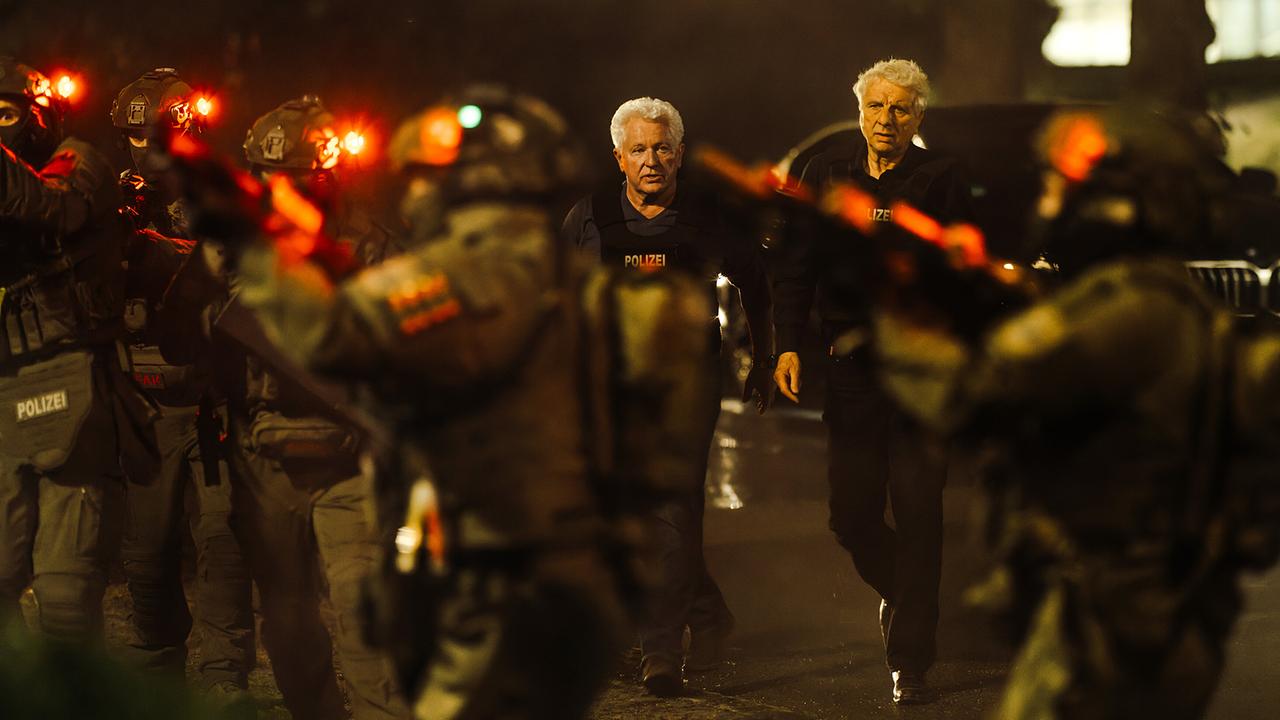 Kriminalhauptkommissar Ivo Batic und Kriminalhauptkommissar Franz Leitmayr in Spezialausrüstung mit den SEK Beamten nachts vor ihrem Einsatz am Karahaus.