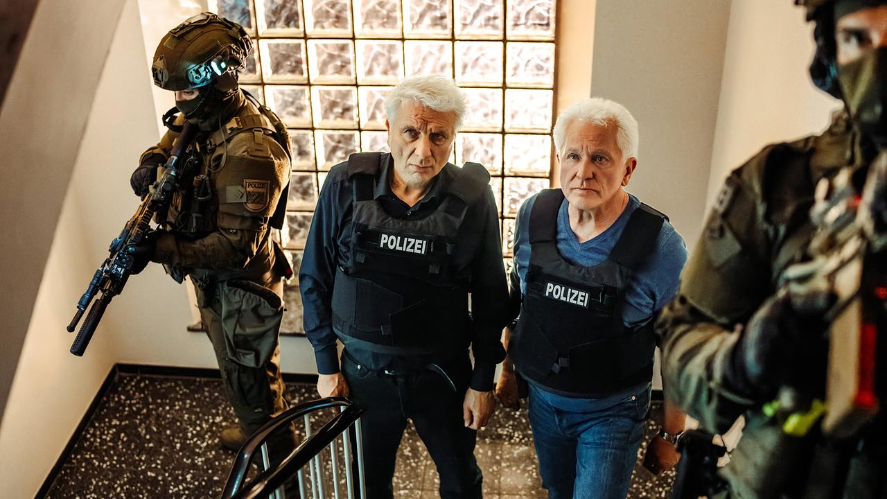 Kriminalhauptkommissar Franz Leitmayr und Kriminalhauptkommissar Ivo Batic stehen mit den SEK Beamten im Treppenhaus des Karahauses.