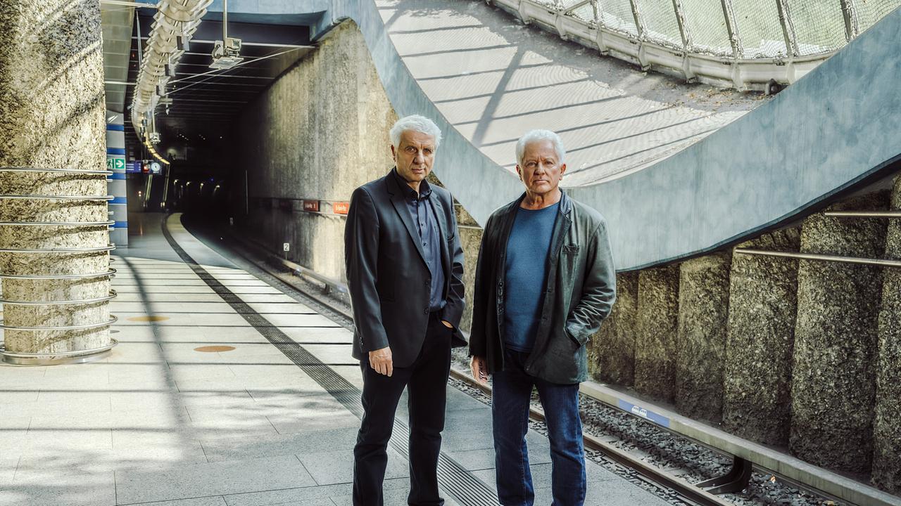 Kriminalhauptkommissar Franz Leitmayr und Kriminalhauptkommissar Ivo Batic  stehen auf einem modernen U-Bahnsteig und blicken in die Kamera.