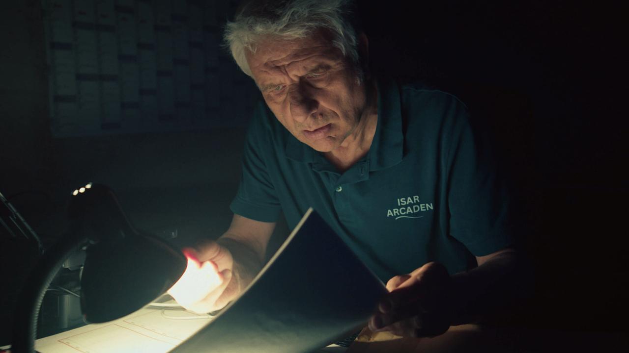 Kriminalhauptkommissar Franz Leitmayr durchsucht nachts den Schreibtisch von Zieringer bei Prime Wave mit einer Taschenlampe auf der Suche nach Hinweisen zu Kara. 