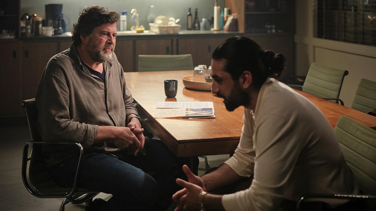 Friedemann Berg und Ramin Taremi sitzen sich an einem Tisch in einer Küche gegenüber und sprechen miteinander.