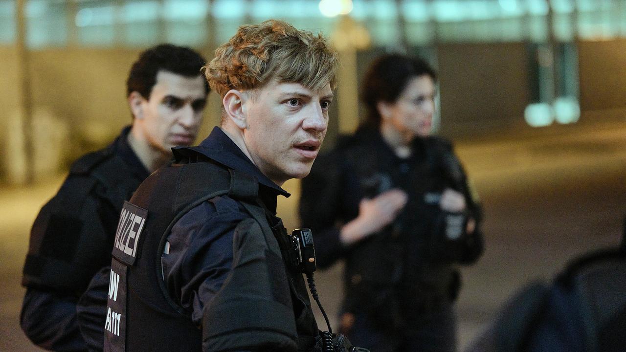 Mehrere Polizeikräfte stehen in dunkler Umgebung beieinander. Unter ihnen ist Jakub, der sich nicht dazu hergeben will, falsche Angaben über den Einsatz zu machen.