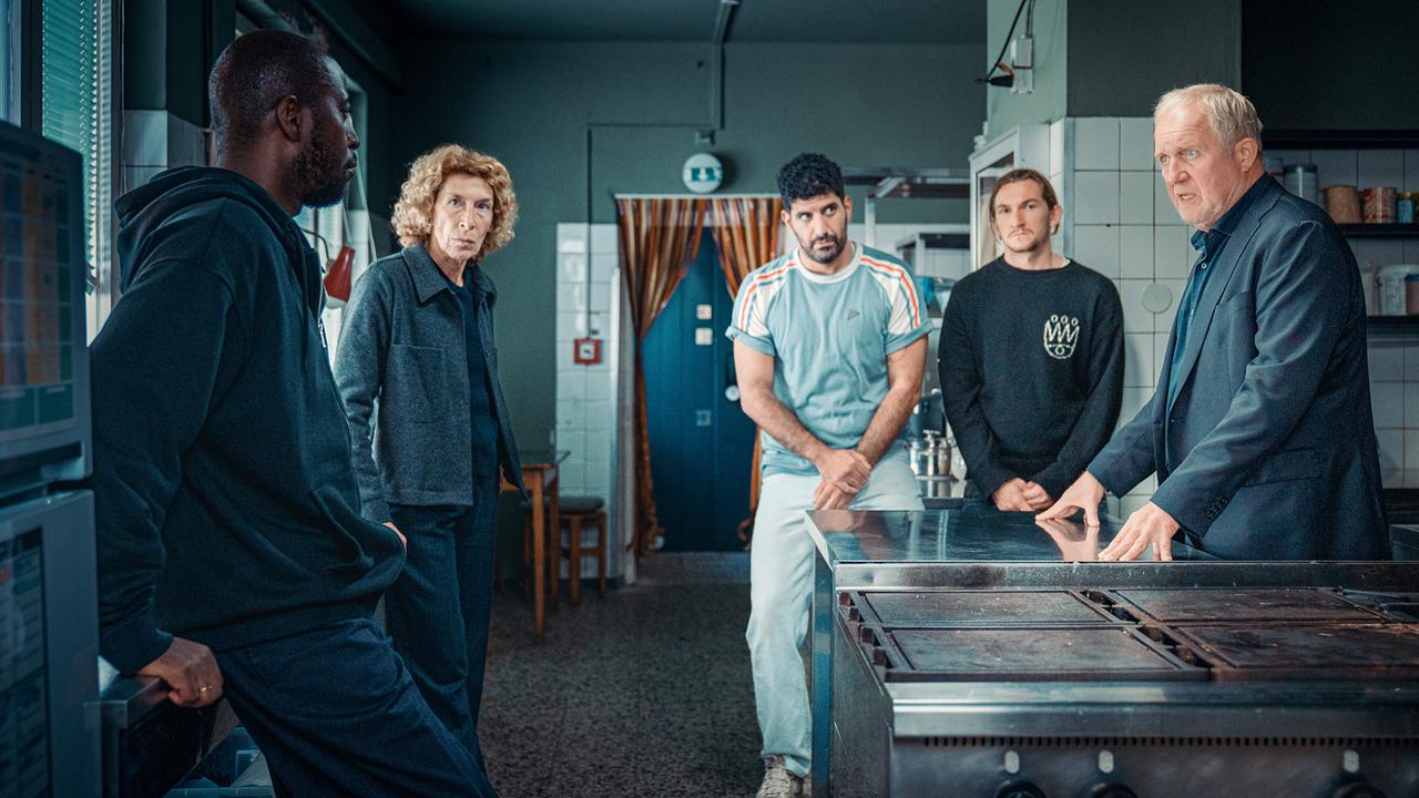 Bibi Fellner und Moritz Eisner stehen mit den Betreuern Femi Olaifa, Araz Barzani und Simon Rechnik in einer Großküche und unterhalten sich.