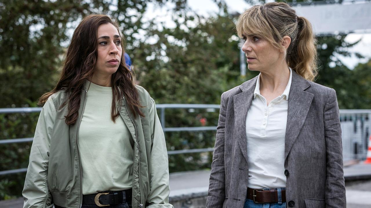 Leichenfund an der Limmat: Kommissarin Tessa Ott und Kommissarin Isabelle Grandjean stehen tagsüber im Freien und blicken einander an.